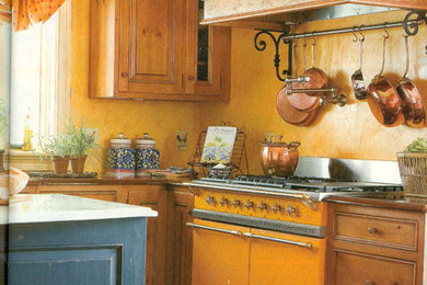 Inspiration for a large rustic u-shaped terra-cotta tile enclosed kitchen remodel in New York with an undermount sink, beaded inset cabinets, distressed cabinets, marble countertops, yellow backsplash, colored appliances and an island
