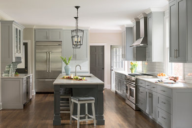 Transitional dark wood floor and brown floor kitchen photo in Charlotte with an undermount sink, shaker cabinets, gray cabinets, white backsplash, subway tile backsplash, stainless steel appliances, an island and white countertops
