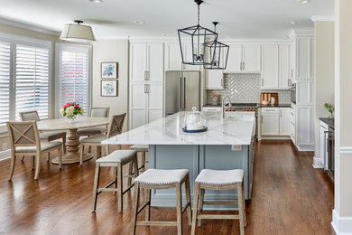 Example of a large transitional l-shaped medium tone wood floor and brown floor eat-in kitchen design in Charlotte with a farmhouse sink, shaker cabinets, white cabinets, quartz countertops, white backsplash, ceramic backsplash, stainless steel appliances, an island and black countertops