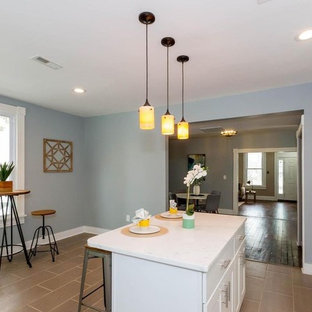 Inspiration for a mid-sized transitional l-shaped eat-in kitchen in Baltimore with a single-bowl sink, recessed-panel cabinets, white cabinets, black appliances, slate floors, with island, pink floor and white benchtop.