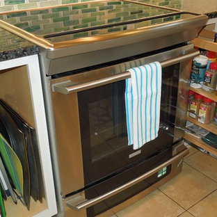 Idéer för ett mellanstort maritimt kök, med en undermonterad diskho, luckor med infälld panel, vita skåp, bänkskiva i återvunnet glas, grönt stänkskydd, stänkskydd i glaskakel, rostfria vitvaror, klinkergolv i keramik och en köksö