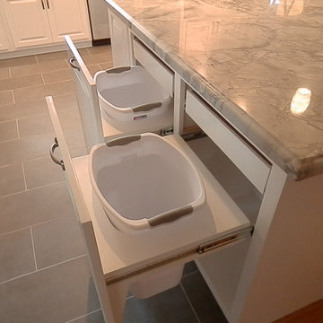 Pull out trash and recycle cabinet with pull out storage shelves above.