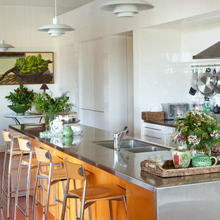 Large contemporary galley kitchen in Brisbane with a double-bowl sink, white cabinets, stainless steel benchtops, white splashback, ceramic splashback, stainless steel appliances, medium hardwood floors and with island.