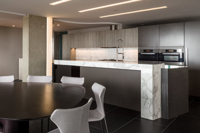 Example of a mid-sized minimalist galley porcelain tile eat-in kitchen design in Chicago with flat-panel cabinets, stone slab backsplash, stainless steel appliances, an island, white backsplash, a double-bowl sink, gray cabinets and marble countertops