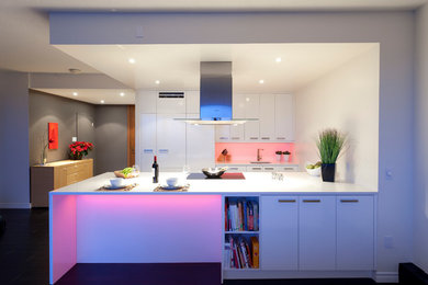 На фото: параллельная кухня среднего размера в стиле модернизм с плоскими фасадами, белыми фасадами, техникой под мебельный фасад, обеденным столом, врезной мойкой, белым фартуком и полуостровом с