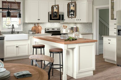 Eat-in kitchen - large l-shaped brown floor eat-in kitchen idea in Other with a farmhouse sink, white cabinets, gray backsplash, stainless steel appliances, an island and gray countertops