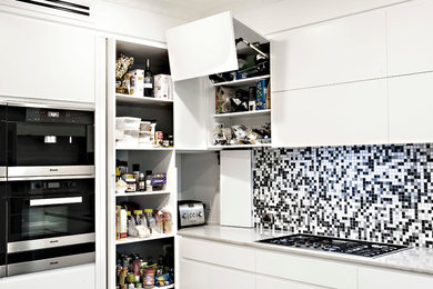Modern inredning av ett mellanstort kök, med en undermonterad diskho, släta luckor, vita skåp, marmorbänkskiva, flerfärgad stänkskydd, stänkskydd i porslinskakel, svarta vitvaror, mellanmörkt trägolv och en köksö