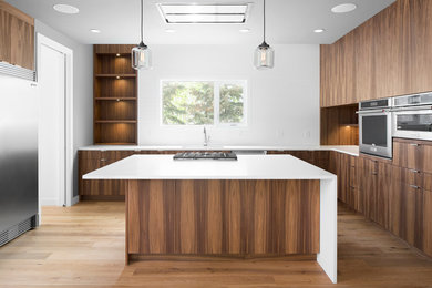 This is an example of a medium sized contemporary l-shaped kitchen in Calgary with a double-bowl sink, flat-panel cabinets, medium wood cabinets, engineered stone countertops, white splashback, ceramic splashback, stainless steel appliances, medium hardwood flooring and an island.