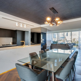 This is an example of a large contemporary galley eat-in kitchen in Sydney with an undermount sink, flat-panel cabinets, dark wood cabinets, white splashback, panelled appliances, medium hardwood floors, with island, brown floor and white benchtop.