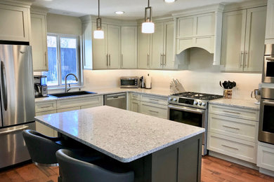 Example of a small transitional l-shaped medium tone wood floor and brown floor open concept kitchen design in Oklahoma City with a drop-in sink, shaker cabinets, quartz countertops, white backsplash, porcelain backsplash, stainless steel appliances, an island and white countertops