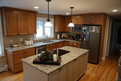 This is an example of a medium sized traditional l-shaped kitchen/diner in Bridgeport with a submerged sink, recessed-panel cabinets, medium wood cabinets, granite worktops, stainless steel appliances, light hardwood flooring and an island.