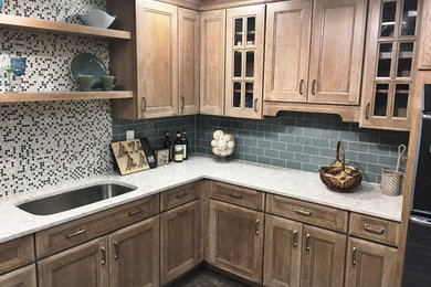 Mid-sized elegant l-shaped dark wood floor and brown floor enclosed kitchen photo in Philadelphia with an undermount sink, recessed-panel cabinets, light wood cabinets, quartzite countertops, gray backsplash, glass tile backsplash, stainless steel appliances and a peninsula