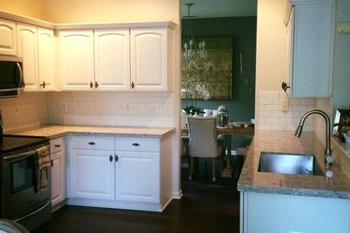 Enclosed kitchen - mid-sized transitional u-shaped dark wood floor enclosed kitchen idea in Indianapolis with an undermount sink, white cabinets, white backsplash, subway tile backsplash, stainless steel appliances and no island