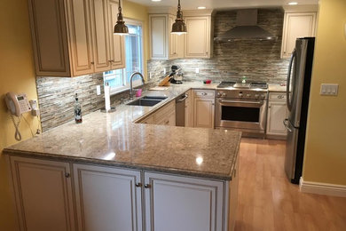 Exempel på ett stort klassiskt kök, med en dubbel diskho, luckor med upphöjd panel, beige skåp, grått stänkskydd, stänkskydd i stickkakel, rostfria vitvaror, ljust trägolv, en halv köksö, beiget golv och granitbänkskiva