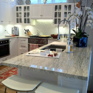 Modelo de cocina comedor en U, minimalista, de tamaño medio, con fregadero bajoencimera, armarios con puertas mallorquinas, puertas de armario blancas, encimera de granito, salpicadero blanco, salpicadero de azulejos tipo metro, electrodomésticos de acero inoxidable, suelo de madera en tonos medios y península
