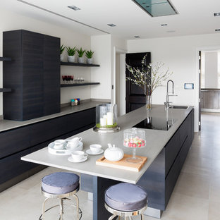 This is an example of a medium sized contemporary single-wall kitchen in London with a submerged sink, flat-panel cabinets, blue cabinets, quartz worktops, integrated appliances, an island, beige floors and grey worktops.