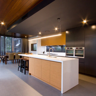 Inspiration for a contemporary galley eat-in kitchen in Brisbane with flat-panel cabinets, black cabinets, stainless steel appliances, with island and grey floor.