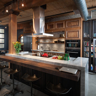 Photo of an industrial eat-in kitchen in Toronto with an undermount sink, raised-panel cabinets, medium wood cabinets, concrete floors, with island and stainless steel appliances.