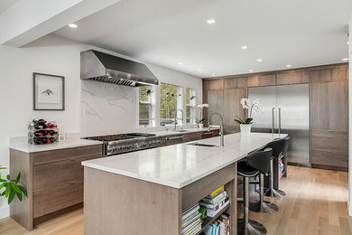 Example of a large trendy l-shaped light wood floor and beige floor open concept kitchen design in Seattle with an undermount sink, flat-panel cabinets, medium tone wood cabinets, white backsplash, stainless steel appliances, an island, white countertops, quartz countertops and stone slab backsplash