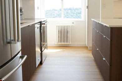 Modelo de cocina minimalista pequeña con armarios con paneles lisos, encimera de cuarzo compacto, electrodomésticos de acero inoxidable, una isla y encimeras blancas