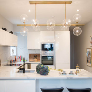 Photo of a medium sized contemporary u-shaped kitchen in London with a submerged sink, flat-panel cabinets, white cabinets, white splashback, a breakfast bar and white worktops.