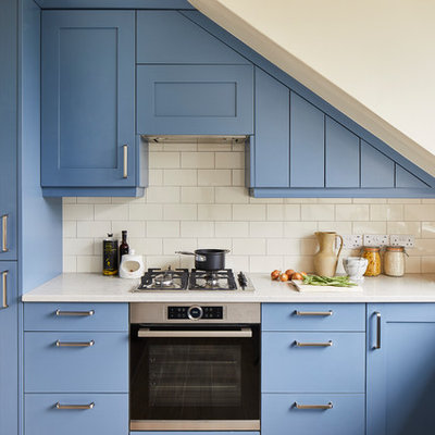 Transitional l-shaped kitchen photo in London with shaker cabinets, blue cabinets, white backsplash, subway tile backsplash, stainless steel appliances and white countertops