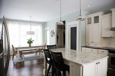 Example of a mid-sized arts and crafts u-shaped medium tone wood floor eat-in kitchen design in Grand Rapids with an undermount sink, shaker cabinets, white cabinets, granite countertops, white backsplash, subway tile backsplash, stainless steel appliances and an island