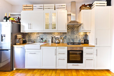 Bohemian kitchen in London with wood worktops, blue splashback, ceramic splashback and stainless steel appliances.