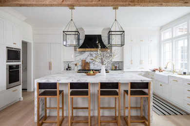 Open concept kitchen - transitional u-shaped light wood floor and white floor open concept kitchen idea in New York with a farmhouse sink, shaker cabinets, white cabinets, marble countertops, multicolored backsplash, marble backsplash, paneled appliances, an island and multicolored countertops