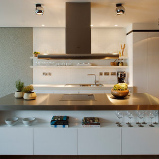 Medium sized contemporary l-shaped kitchen in London with a double-bowl sink, flat-panel cabinets, white cabinets, white splashback, mosaic tiled splashback, stainless steel appliances, light hardwood flooring, an island and beige floors.
