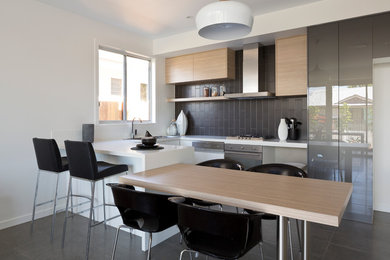 Moderne Wohnküche in U-Form mit Doppelwaschbecken, hellen Holzschränken, Küchenrückwand in Grau, Rückwand aus Metrofliesen, Küchengeräten aus Edelstahl und Keramikboden in Brisbane