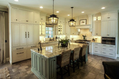 Foto de cocina clásica con armarios con rebordes decorativos, puertas de armario blancas, electrodomésticos de acero inoxidable y una isla