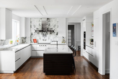Example of a trendy u-shaped medium tone wood floor and brown floor kitchen design in Philadelphia with an undermount sink, flat-panel cabinets, white cabinets, multicolored backsplash, an island and white countertops