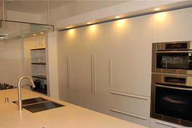 Foto de cocina lineal actual grande abierta con armarios con paneles lisos, puertas de armario blancas y una isla