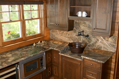 Modelo de cocina rústica con armarios con rebordes decorativos, puertas de armario de madera en tonos medios, encimera de mármol y electrodomésticos de acero inoxidable