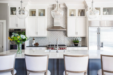 Inspiration for a transitional galley kitchen remodel in Dallas with an undermount sink, shaker cabinets, white cabinets, gray backsplash, subway tile backsplash, stainless steel appliances, an island and white countertops
