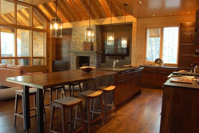 Example of a mid-sized trendy l-shaped dark wood floor open concept kitchen design in Charlotte with an island, an undermount sink, flat-panel cabinets, medium tone wood cabinets, soapstone countertops, brown backsplash and stainless steel appliances