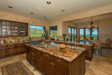Enclosed kitchen - mid-sized mediterranean u-shaped ceramic tile and brown floor enclosed kitchen idea in Los Angeles with a double-bowl sink, raised-panel cabinets, dark wood cabinets, granite countertops, multicolored backsplash, stone tile backsplash, stainless steel appliances, two islands and brown countertops