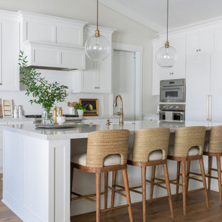 Large transitional open concept kitchen photos - Large transitional l-shaped medium tone wood floor, brown floor and vaulted ceiling open concept kitchen photo in Sacramento with a farmhouse sink, shaker cabinets, white cabinets, quartz countertops, white backsplash, ceramic backsplash, stainless steel appliances, an island and gray countertops