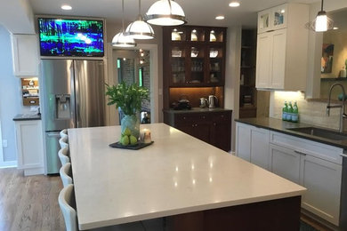 This is an example of a large retro kitchen/diner in DC Metro with glass-front cabinets, white cabinets, stainless steel appliances, light hardwood flooring and an island.