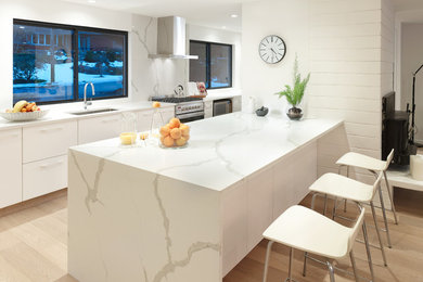 Idéer för att renovera ett stort funkis kök, med en undermonterad diskho, släta luckor, vita skåp, marmorbänkskiva, vitt stänkskydd, stänkskydd i marmor, rostfria vitvaror, ljust trägolv, en halv köksö och beiget golv