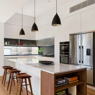 Inspiration for a mid-sized contemporary l-shaped eat-in kitchen in Sydney with flat-panel cabinets, white cabinets, quartz benchtops, grey splashback, ceramic splashback, stainless steel appliances, medium hardwood floors, with island, brown floor and white benchtop.