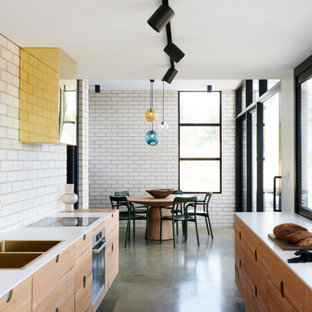 This is an example of a contemporary galley eat-in kitchen in Adelaide with a double-bowl sink, flat-panel cabinets, medium wood cabinets, quartz benchtops, white splashback, brick splashback, stainless steel appliances, concrete floors, no island, grey floor and white benchtop.