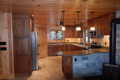 Foto di una grande cucina stile rurale con lavello sottopiano, ante con riquadro incassato, ante in legno scuro, paraspruzzi beige, elettrodomestici da incasso, penisola e pavimento marrone