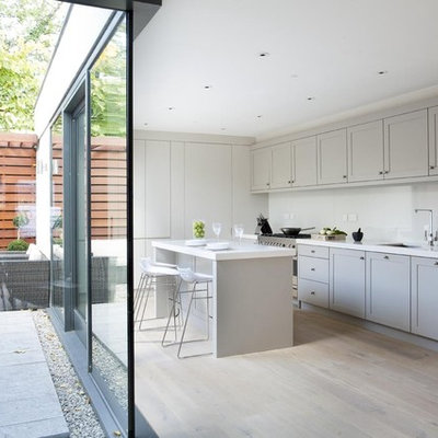 Inspiration for a contemporary l-shaped kitchen remodel in Dublin with an undermount sink, shaker cabinets, gray cabinets, white backsplash, glass sheet backsplash and stainless steel appliances