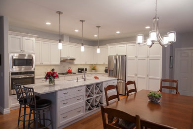 Mid-sized transitional l-shaped medium tone wood floor open concept kitchen photo in Other with a double-bowl sink, shaker cabinets, white cabinets, quartz countertops, gray backsplash, porcelain backsplash, stainless steel appliances and an island