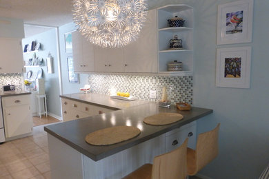 Example of a mid-sized minimalist u-shaped eat-in kitchen design in Tampa with an undermount sink, flat-panel cabinets, white cabinets, concrete countertops, gray backsplash, mosaic tile backsplash and white appliances