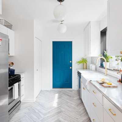 Inspiration for a mid-sized transitional galley travertine floor and gray floor enclosed kitchen remodel in Chicago with a farmhouse sink, white cabinets, white backsplash, stainless steel appliances, no island, flat-panel cabinets, marble countertops and porcelain backsplash