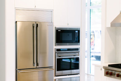 Foto de cocina comedor contemporánea con armarios con paneles lisos, puertas de armario blancas, encimera de acrílico, electrodomésticos de acero inoxidable y suelo de madera en tonos medios
