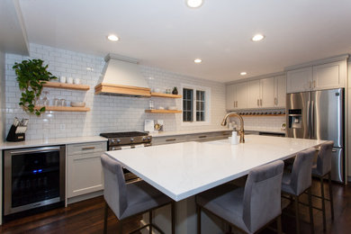 Inspiration for a mid-sized transitional l-shaped dark wood floor and brown floor enclosed kitchen remodel in Toronto with an undermount sink, shaker cabinets, white cabinets, quartz countertops, white backsplash, subway tile backsplash, stainless steel appliances, an island and white countertops